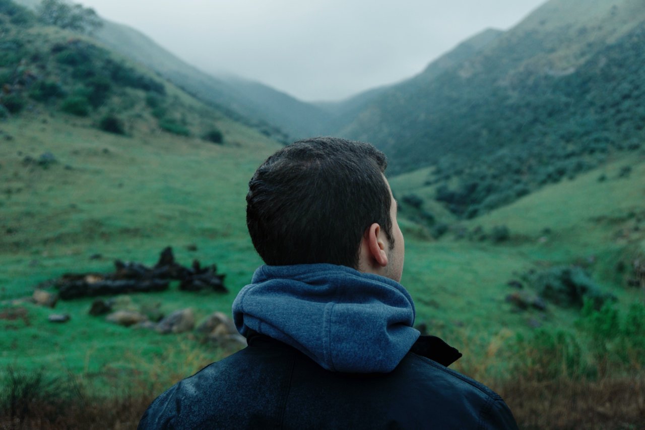 Man looking out over a field and mountains