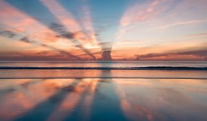 Sun Setting Behind Clouds with Water Reflection